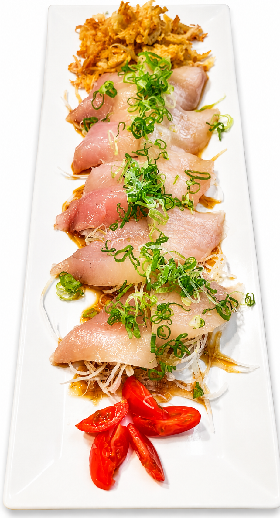 A long white rectangular platter holding a sashimi-style fish dish with pale pink fish slices, green onion garnish, shredded white radish, a small pile of golden fried cracker pieces, and red tomato slices on a white background.