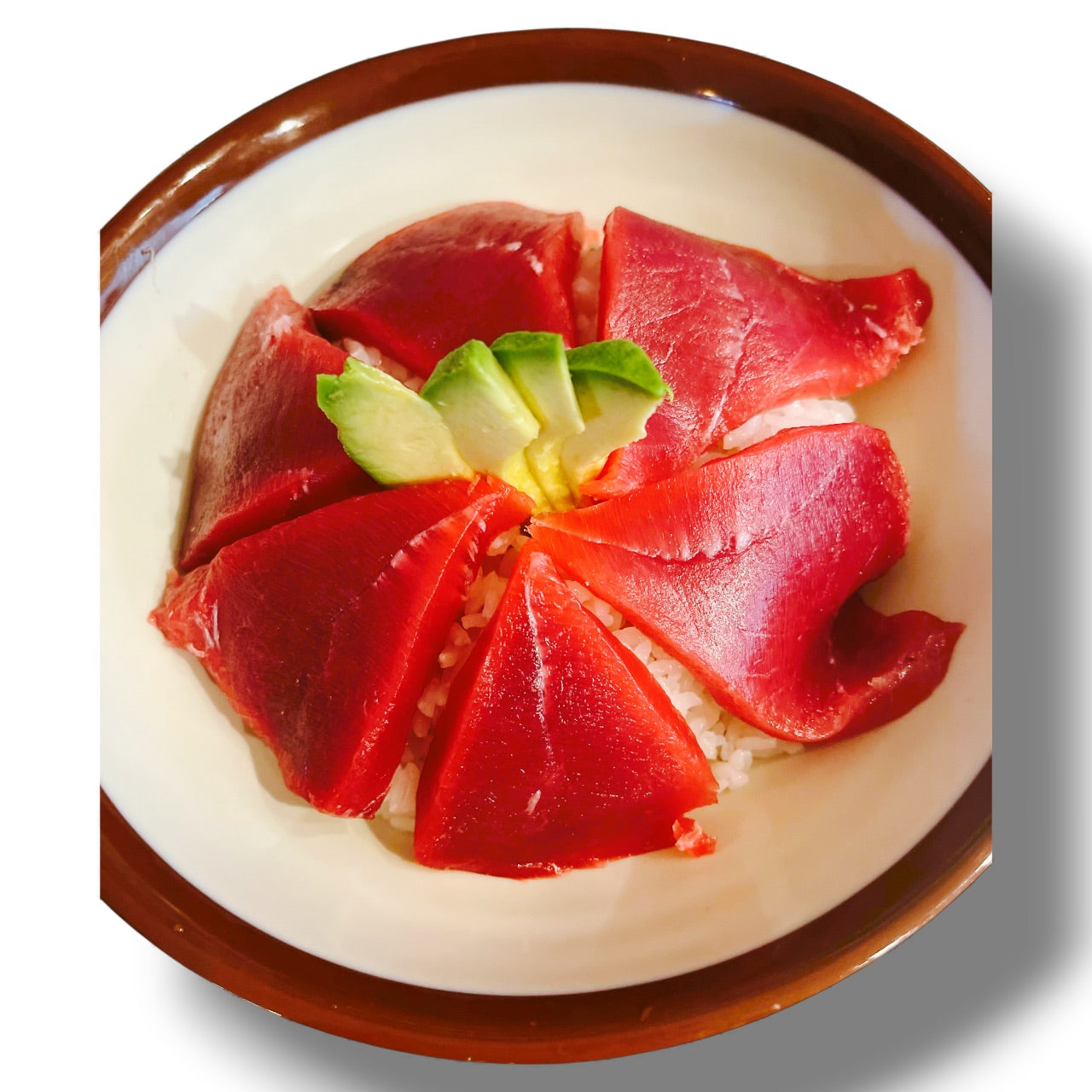 Sashimi dish with red fish slices on a white plate with a brown rim