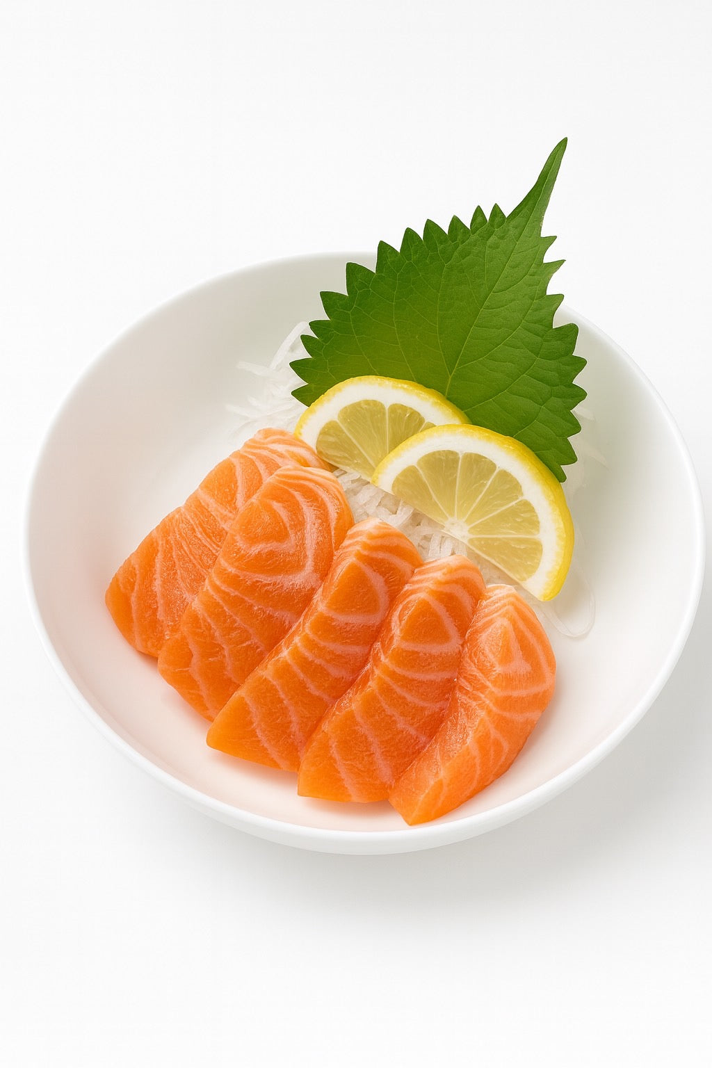 Salmon sashimi with lemon wedges and a green leaf on a white plate.