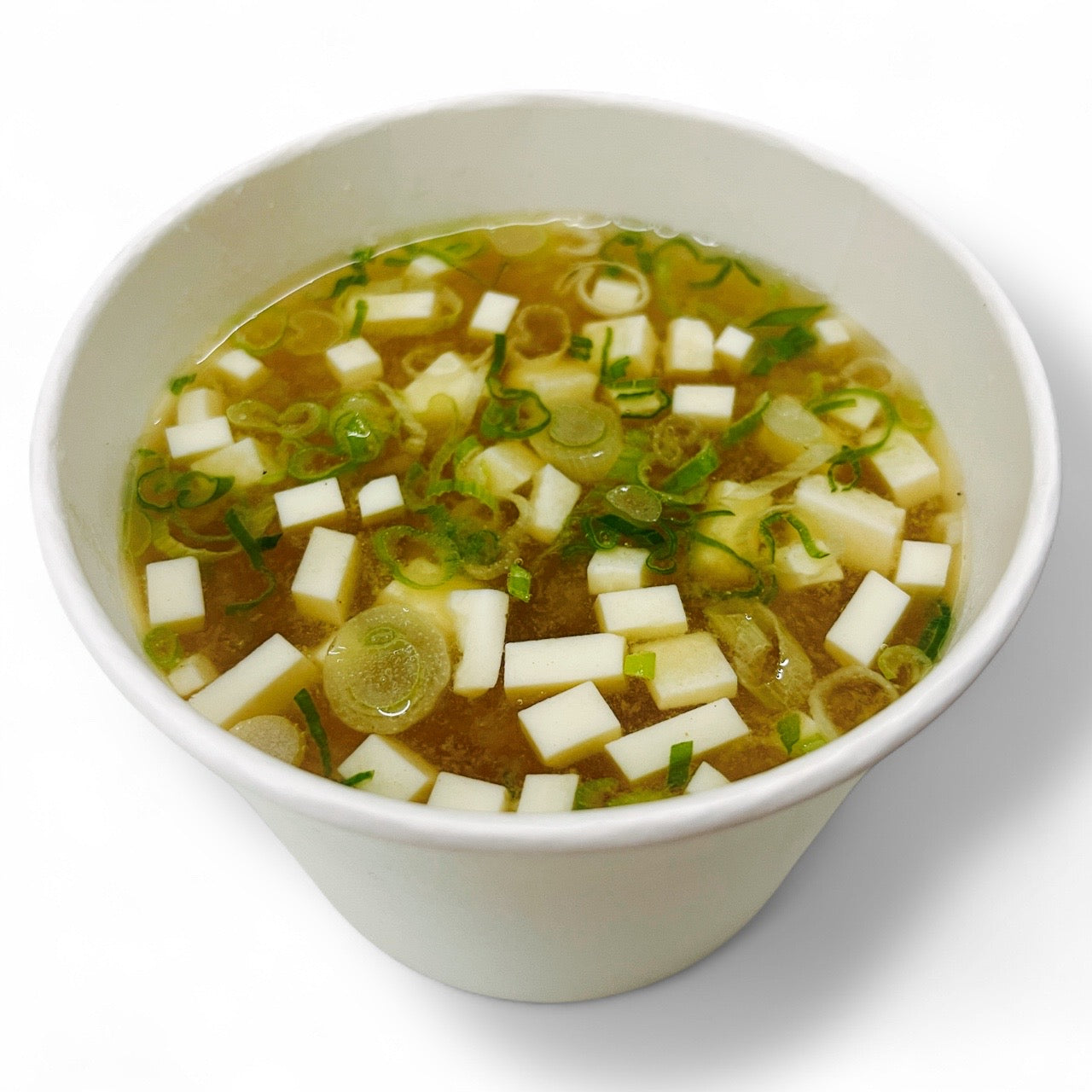Classic miso soup with tofu cubes, green onions, and seaweed served in a to-go cup — warm Japanese miso soup On a white background 