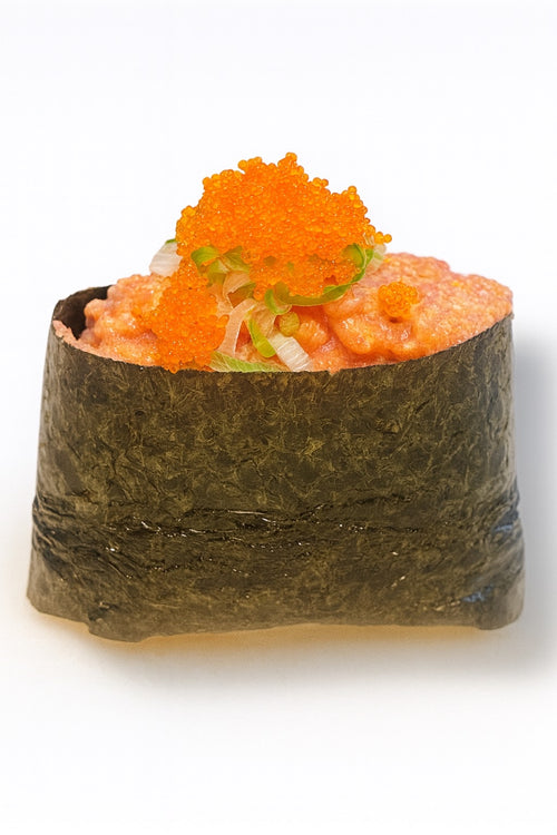 Spicy tuna gunkan sushi made with fresh minced tuna in a spicy sauce, wrapped in seaweed and topped with bright orange tobiko on a white background